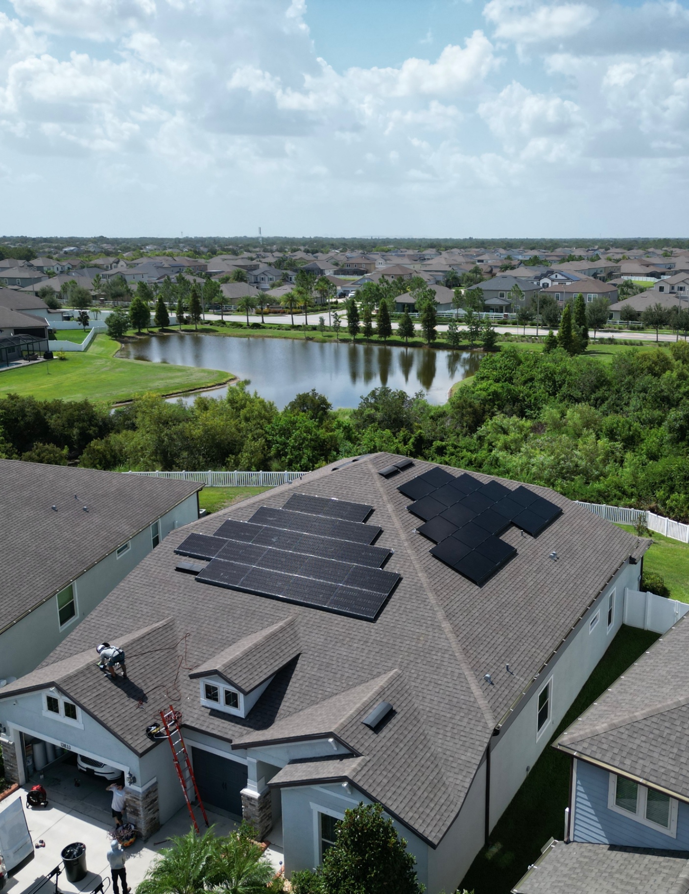 Florida home with a completed rooftop solar array, surrounded by greenery and a neighborhood lake